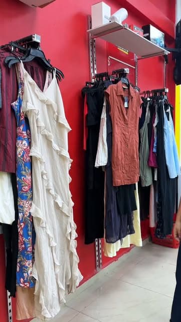 Vestidos colgados sobre pared roja de la tienda